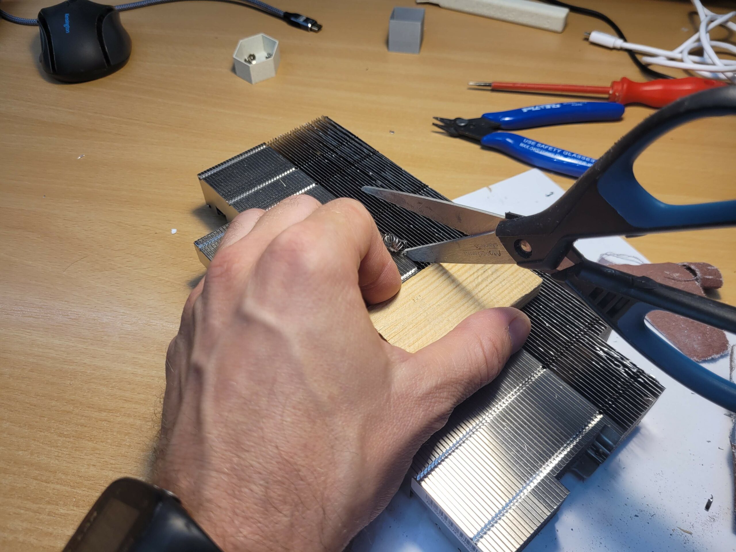 Cutting the metal strips on the detached BC-250 heatsink with scissors