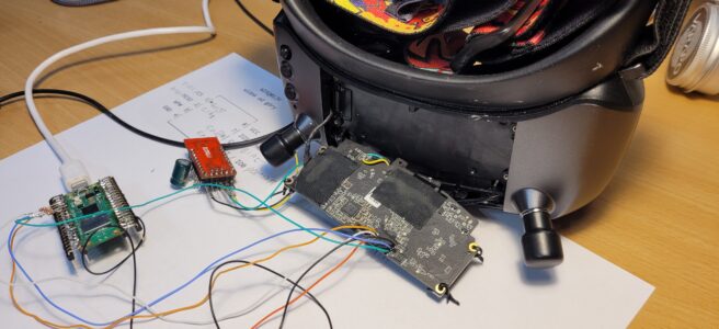 Disassembled Walksnail Avatar X goggles with Raspberry Pi Pico programmer wiring connected to the mainboard