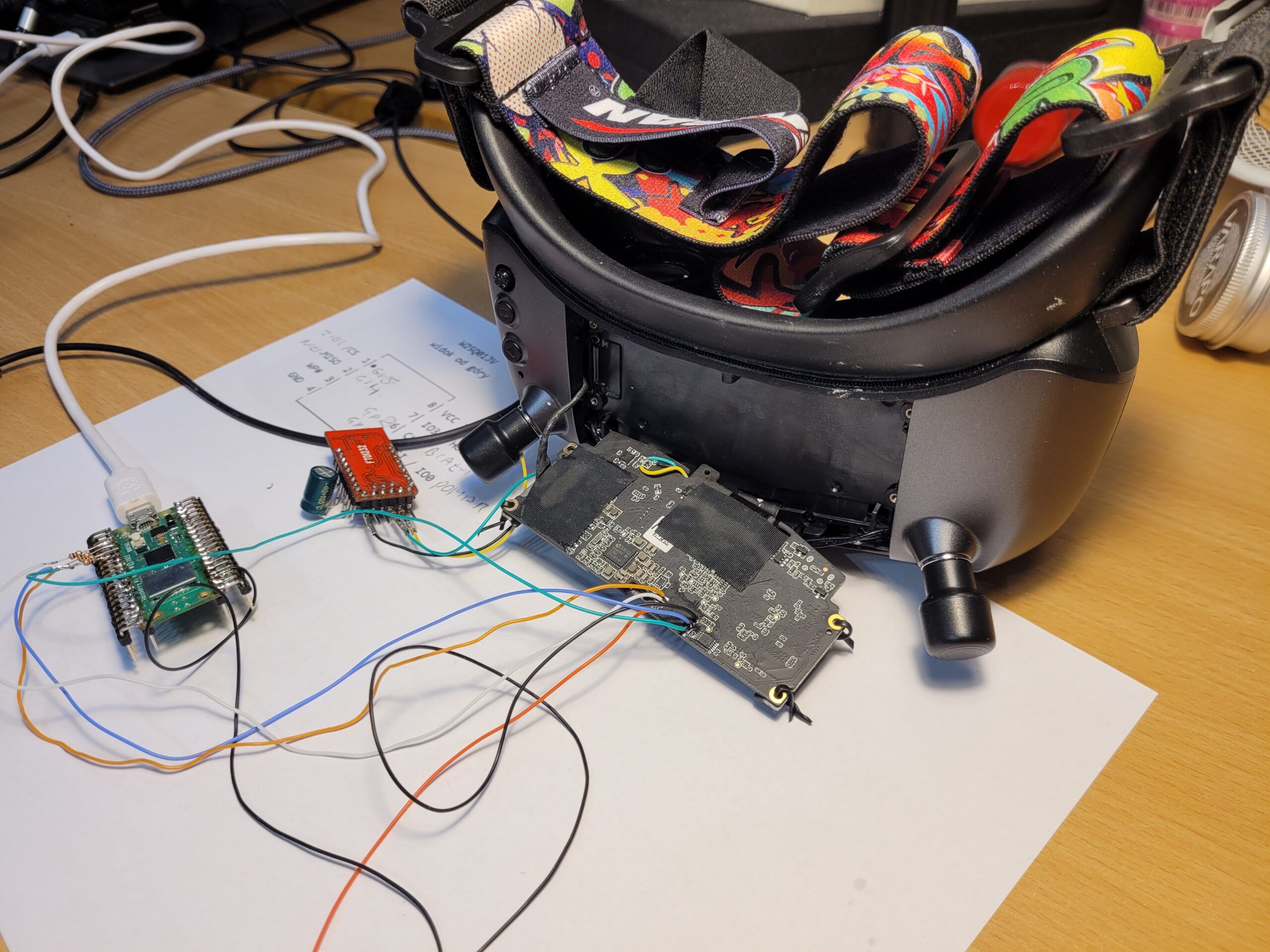 Disassembled Walksnail Avatar X goggles with Raspberry Pi Pico programmer wiring connected to the mainboard